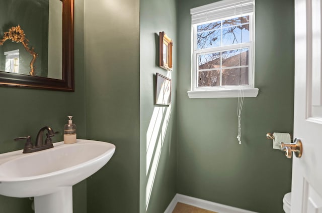 bathroom featuring baseboards, a sink, and toilet