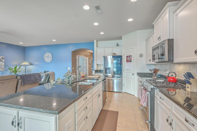 kitchen with sink, a center island with sink, light tile patterned floors, stainless steel appliances, and white cabinets