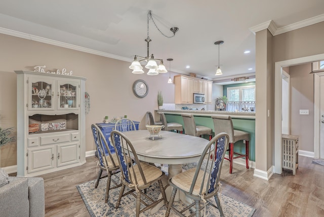 dining space featuring ornamental molding, light wood-type flooring, and a chandelier