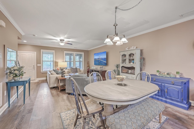 dining room with ceiling fan with notable chandelier, crown molding, and light hardwood / wood-style flooring