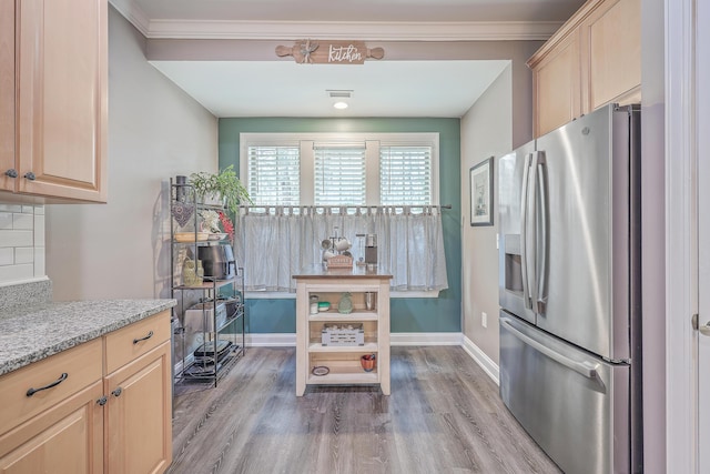 kitchen with wood-type flooring, stainless steel fridge with ice dispenser, ornamental molding, light brown cabinetry, and light stone counters