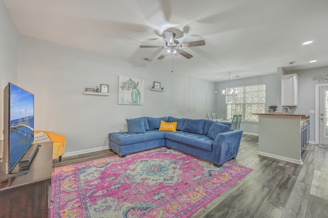 living room featuring ceiling fan with notable chandelier and dark hardwood / wood-style floors