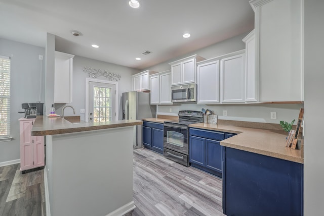 kitchen with white cabinetry, stainless steel appliances, blue cabinets, kitchen peninsula, and light hardwood / wood-style floors