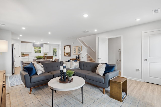 living room featuring stairway, light wood-type flooring, visible vents, and recessed lighting