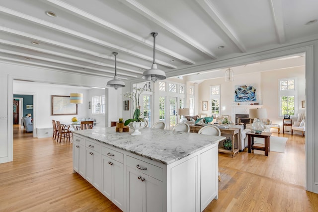 kitchen featuring open floor plan, a center island, decorative light fixtures, and white cabinets