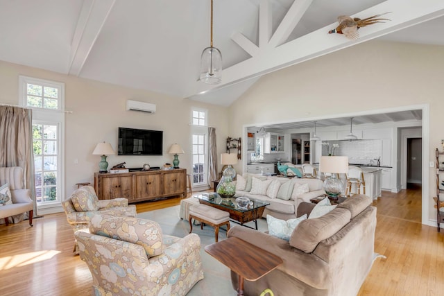 living area with an AC wall unit, light wood-type flooring, and beam ceiling