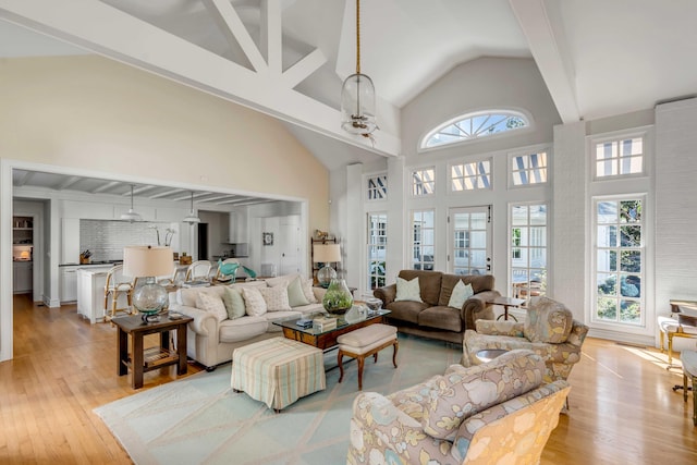 living area featuring plenty of natural light, high vaulted ceiling, and light wood-type flooring