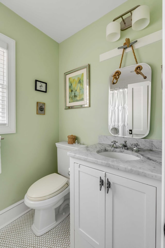 bathroom featuring toilet, tile patterned flooring, baseboards, and vanity