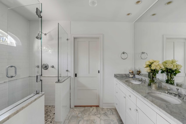 bathroom with marble finish floor, a sink, a shower stall, and double vanity