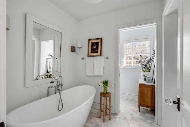 full bathroom featuring a freestanding bath, marble finish floor, and baseboards