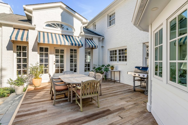 wooden terrace with outdoor dining space and a grill