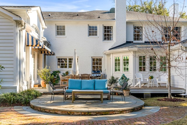 rear view of property with a patio, a chimney, an outdoor hangout area, a deck, and brick siding