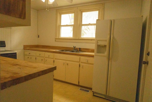 kitchen featuring white refrigerator with ice dispenser, range, ceiling fan, and sink