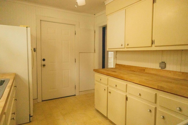 kitchen featuring white fridge, white cabinetry, and ornamental molding