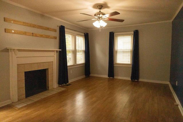 unfurnished living room with a fireplace, wood-type flooring, a wealth of natural light, and ornamental molding