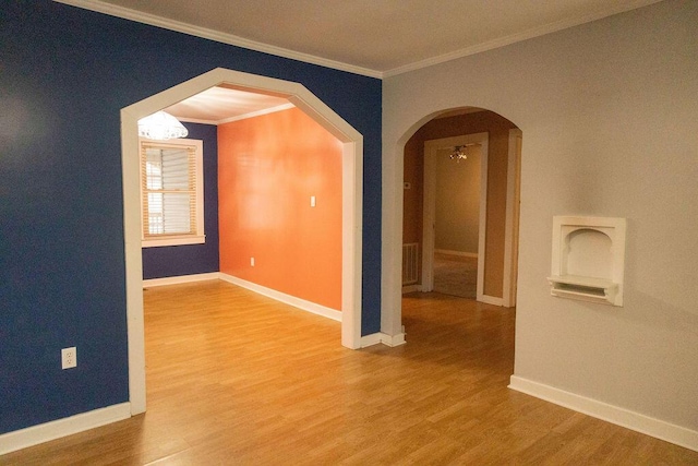 spare room with hardwood / wood-style floors, an inviting chandelier, and ornamental molding