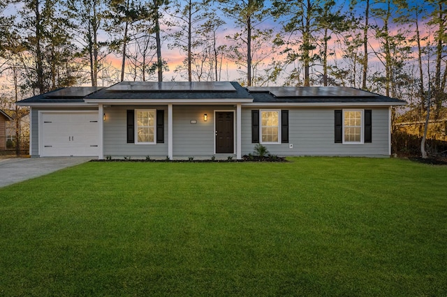 ranch-style house with solar panels, a garage, and a yard