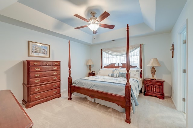 carpeted bedroom featuring ceiling fan and a tray ceiling