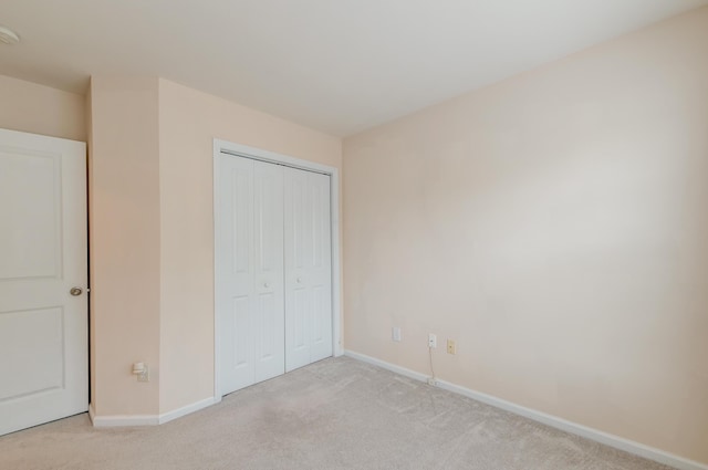 unfurnished bedroom with light carpet and a closet