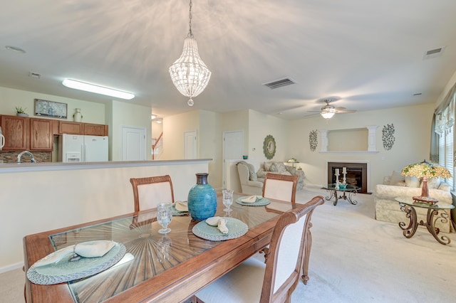 dining area with sink, light colored carpet, and ceiling fan