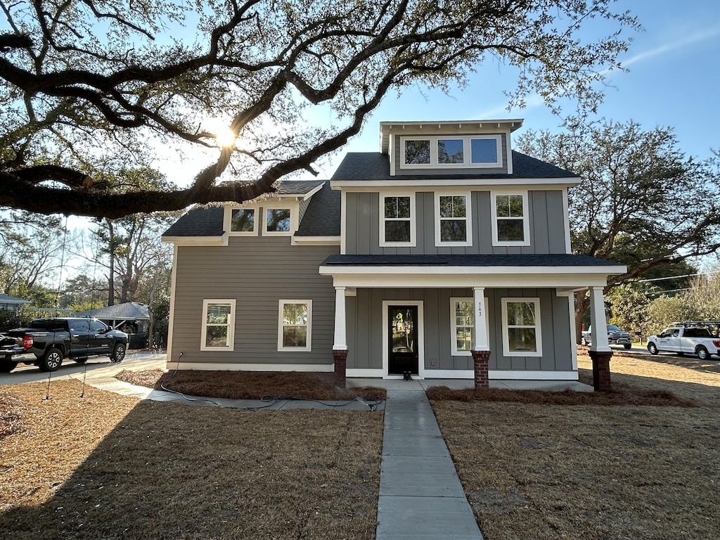traditional style home with a porch, roof with shingles, and board and batten siding