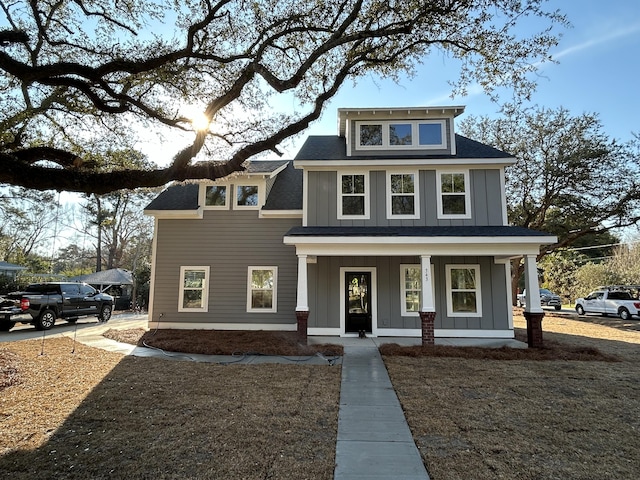 traditional style home with a porch, roof with shingles, and board and batten siding