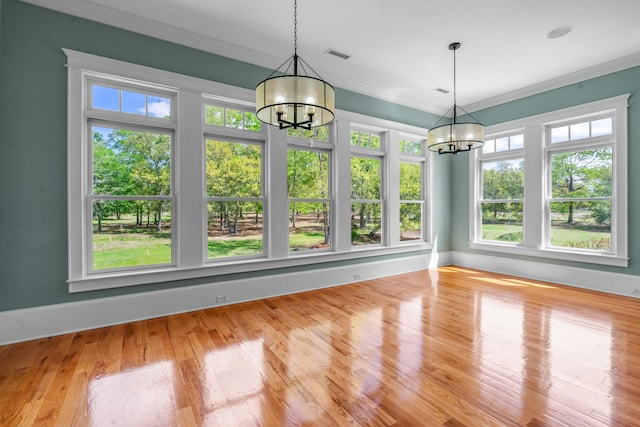unfurnished dining area with baseboards, an inviting chandelier, ornamental molding, visible vents, and wood finished floors