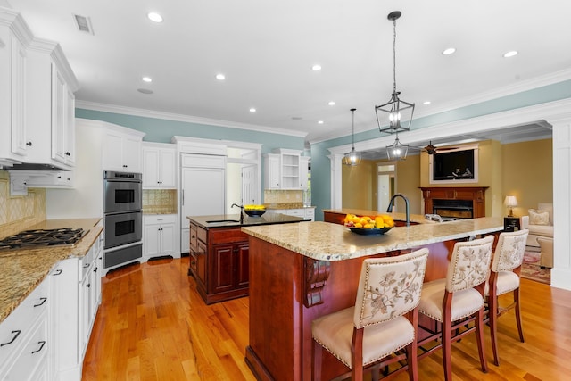 kitchen featuring a fireplace, visible vents, a warming drawer, a large island, and appliances with stainless steel finishes