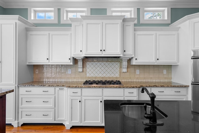 kitchen with a sink, white cabinets, stainless steel gas stovetop, and a wealth of natural light