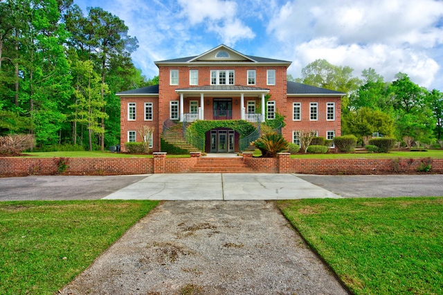 view of front of home featuring brick siding, a porch, french doors, and a front lawn