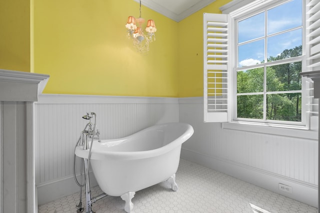 bathroom featuring a freestanding bath, an inviting chandelier, a wainscoted wall, and crown molding