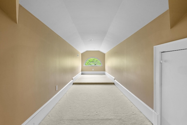 hallway featuring carpet floors, baseboards, and vaulted ceiling