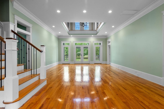 unfurnished living room with stairway, hardwood / wood-style floors, baseboards, and crown molding