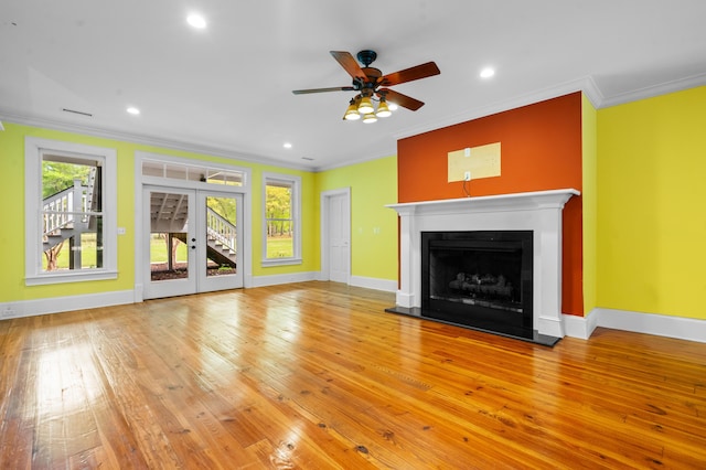 unfurnished living room with a wealth of natural light, hardwood / wood-style floors, ornamental molding, and ceiling fan