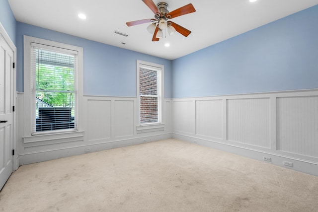 carpeted empty room featuring ceiling fan, wainscoting, visible vents, and recessed lighting