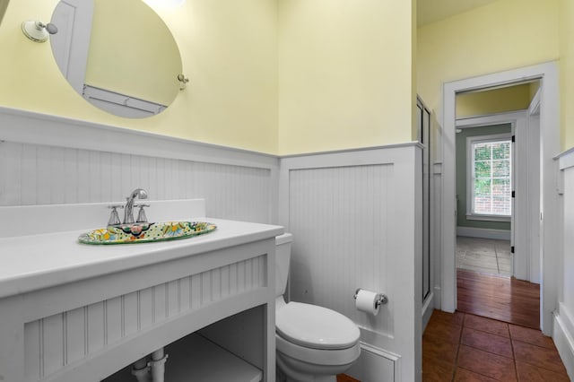 bathroom featuring toilet, a stall shower, wainscoting, and tile patterned floors