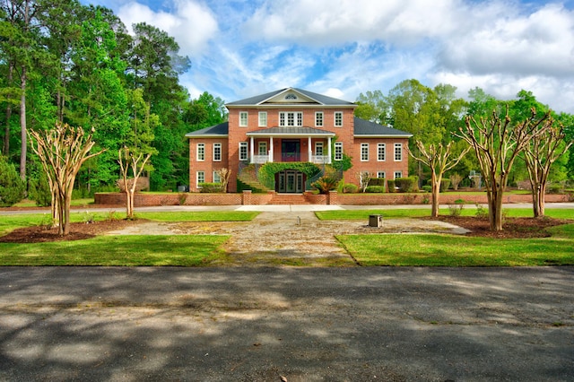 colonial inspired home with a balcony and a front lawn