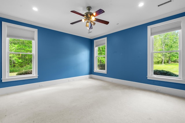 carpeted empty room with crown molding, visible vents, and a healthy amount of sunlight