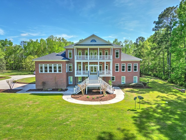 rear view of house featuring a yard, covered porch, stairway, brick siding, and a balcony