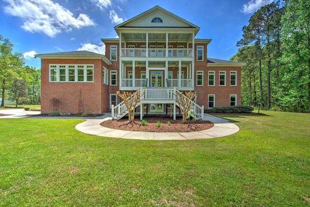 back of property featuring stairway, a yard, brick siding, and a balcony
