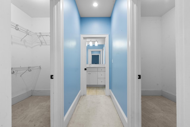 bathroom featuring vanity, baseboards, and a spacious closet