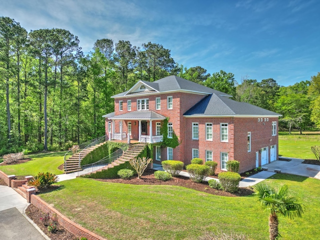 view of front facade featuring concrete driveway, stairway, a front lawn, an attached garage, and brick siding