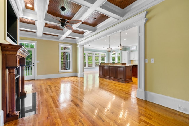 unfurnished living room featuring baseboards, light wood-style flooring, a ceiling fan, ornate columns, and beamed ceiling