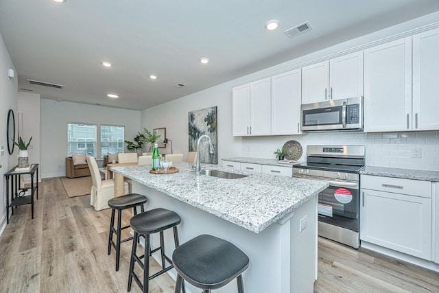902 Twin Rivers Dr, Wando, SC 29492 - kitchen with a kitchen island with sink, visible vents, appliances with stainless steel finishes, a sink, and light wood-style floors