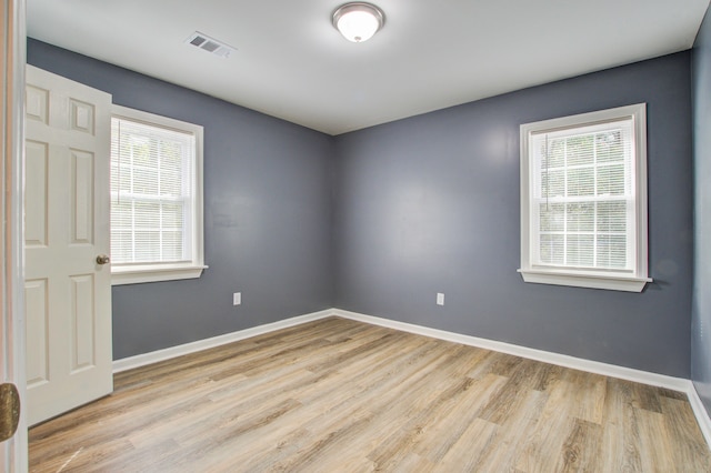 empty room featuring a healthy amount of sunlight and light hardwood / wood-style floors