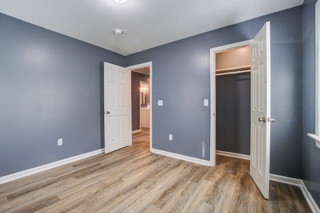 unfurnished bedroom with a walk in closet, a closet, and light hardwood / wood-style flooring