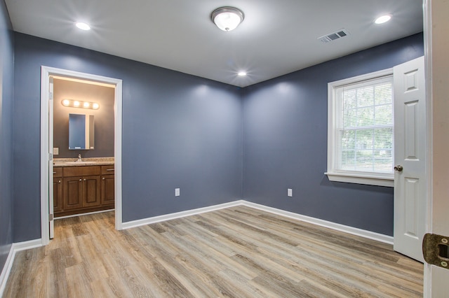 interior space featuring connected bathroom, light hardwood / wood-style flooring, and sink