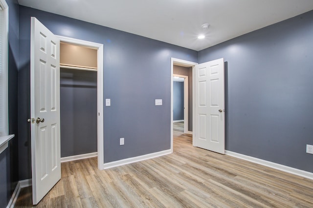 unfurnished bedroom featuring a closet, a spacious closet, and light hardwood / wood-style flooring