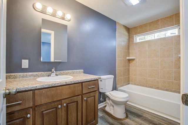 full bathroom with tiled shower / bath, vanity, wood-type flooring, and toilet