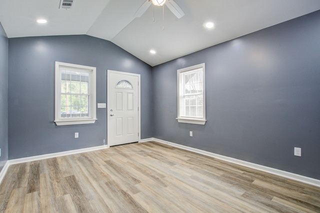 empty room featuring ceiling fan, vaulted ceiling, a wealth of natural light, and light hardwood / wood-style flooring